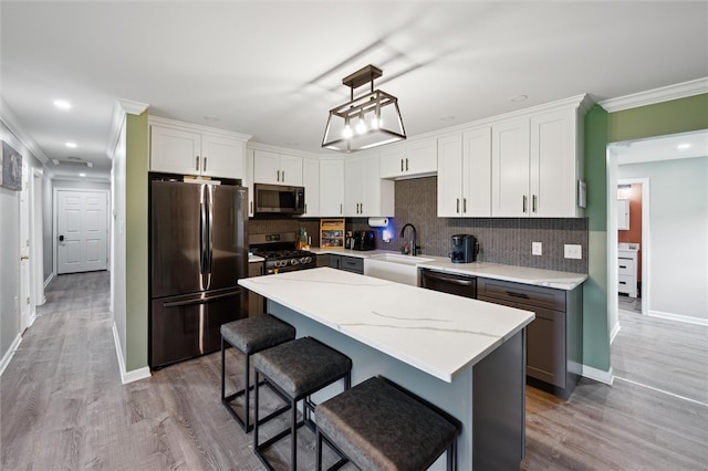 4 Ward St, Canton Twp, PA 15301 - kitchen with appliances with stainless steel finishes, a center island, decorative backsplash, a kitchen bar, and light wood-style floors