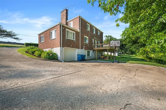 7604 Tyler Rd, Verona, PA 15147 - view of property exterior featuring an attached garage, brick siding, driveway, a chimney, and a deck