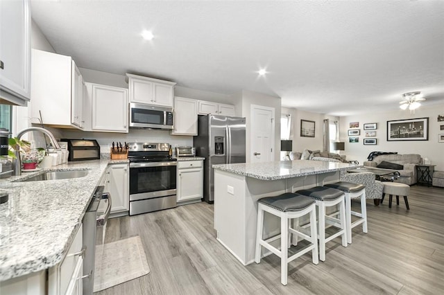 329 Nelson Dr, Monroeville, PA 15146 - kitchen with stainless steel appliances, open floor plan, a breakfast bar, a center island, and light wood-style flooring