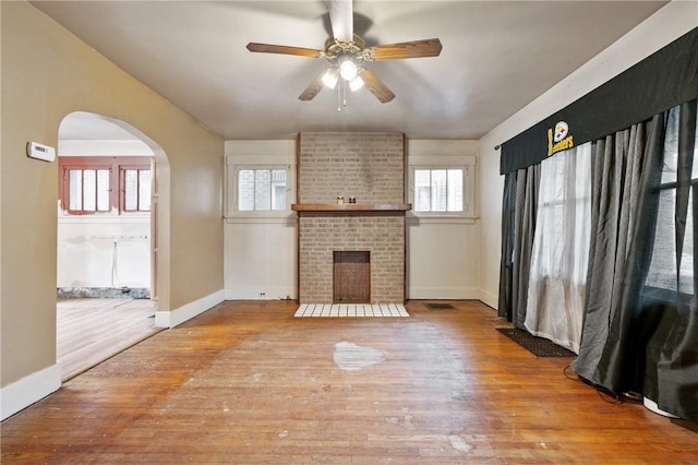 1477 Benton Ave, Brighton Heights, PA 15212 - unfurnished living room featuring ceiling fan, arched walkways, wood finished floors, and a brick fireplace