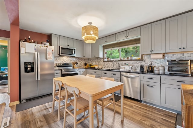 1021 Beechnut St, West Deer, PA 15084 - kitchen with appliances with stainless steel finishes, dark countertops, gray cabinetry, light wood finished floors, and tasteful backsplash