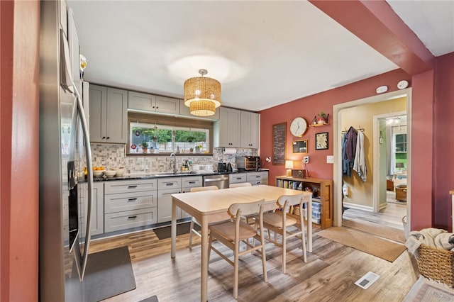 1021 Beechnut St, West Deer, PA 15084 - kitchen featuring dark countertops, decorative backsplash, appliances with stainless steel finishes, gray cabinetry, and light wood-style floors