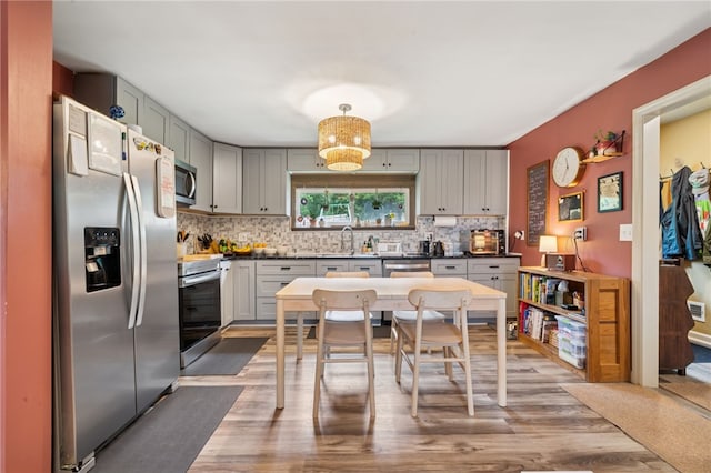 1021 Beechnut St, West Deer, PA 15084 - kitchen featuring stainless steel appliances, wood finished floors, backsplash, gray cabinetry, and dark countertops