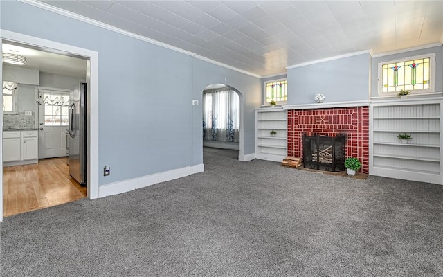 112 Fisk Ave, Avalon, PA 15202 - unfurnished living room with crown molding, arched walkways, carpet floors, a fireplace, and plenty of natural light