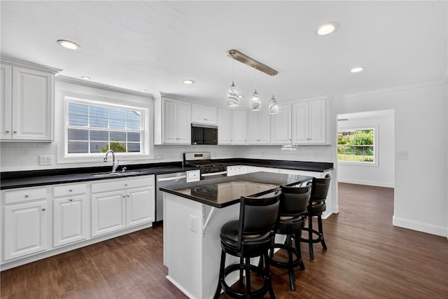 235 Telegraph Rd, Luzerne Twp, PA 15417 - kitchen with stainless steel appliances, dark countertops, tasteful backsplash, a kitchen bar, and dark wood finished floors