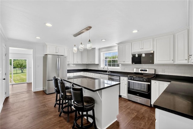 235 Telegraph Rd, Luzerne Twp, PA 15417 - kitchen featuring appliances with stainless steel finishes, dark countertops, a breakfast bar area, white cabinets, and decorative backsplash