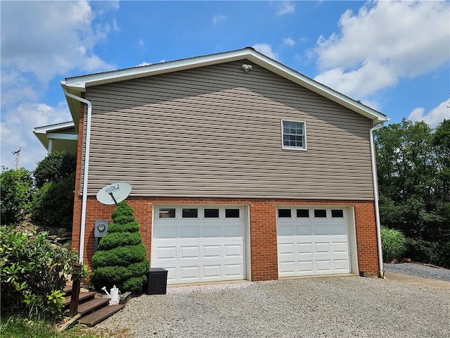 323 Hoon Rd, Oakland Twp, PA 16001 - view of side of property with gravel driveway, a garage, and brick siding