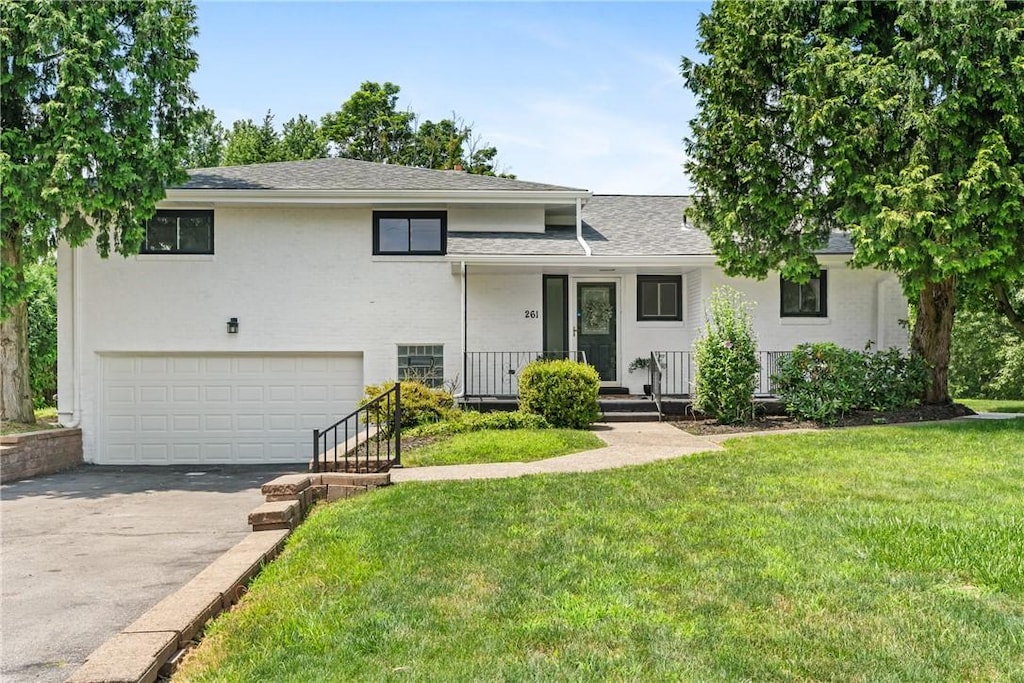 261 Churchill Rd, Wilkins Twp, PA 15235 - tri-level home with a garage, driveway, covered porch, and a front lawn