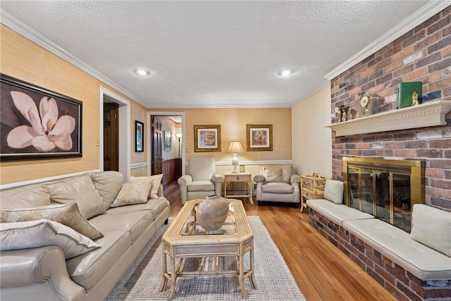 511 Brunswick Dr, Hempfield Twp, PA 15601 - living room featuring wood finished floors, crown molding, a textured ceiling, a brick fireplace, and recessed lighting