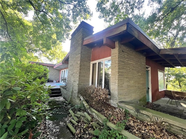 1560 Oneida Dr, Jefferson Hills, PA 15025 - view of property exterior featuring stone siding, a chimney, and a deck