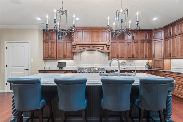 3111 Edelweiss Ct Ste 201, Adams Twp, PA 16046 - kitchen featuring a chandelier, a kitchen island with sink, pendant lighting, dark wood-style flooring, and crown molding