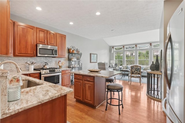 774 Norwegian Spruce Dr, Adams Twp, PA 16046 - kitchen featuring stainless steel appliances, light stone countertops, a breakfast bar, decorative backsplash, and brown cabinets