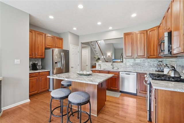 774 Norwegian Spruce Dr, Adams Twp, PA 16046 - kitchen with stainless steel appliances, a kitchen island, a kitchen breakfast bar, backsplash, and light wood-type flooring