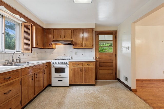 1920 Cheryl Dr, North Huntingdon, PA 15642 - kitchen featuring white range with gas stovetop, under cabinet range hood, tasteful backsplash, light countertops, and brown cabinets