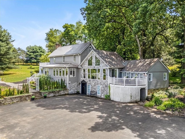 115 Nursery Rd, Forward Twp, PA 16053 - rear view of property featuring stone siding, a chimney, view of scattered trees, and asphalt driveway