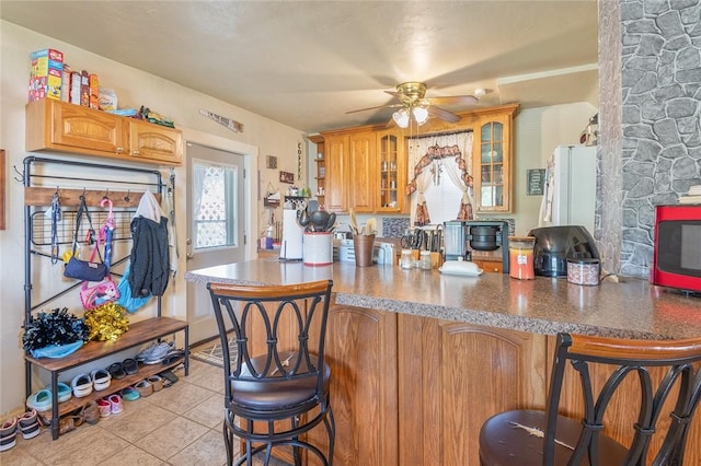 2913 Willett Rd, Brentwood, PA 15227 - kitchen featuring light tile patterned floors, a breakfast bar, ceiling fan, glass insert cabinets, and a peninsula