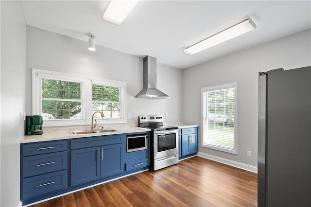 538 Bluegrass Dr, Canonsburg, PA 15317 - kitchen with appliances with stainless steel finishes, wall chimney range hood, blue cabinetry, dark wood-type flooring, and light countertops