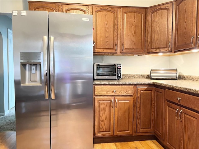 1069 Martin Ave, New Kensington, PA 15068 - kitchen featuring stainless steel refrigerator with ice dispenser, light wood finished floors, brown cabinetry, and light countertops