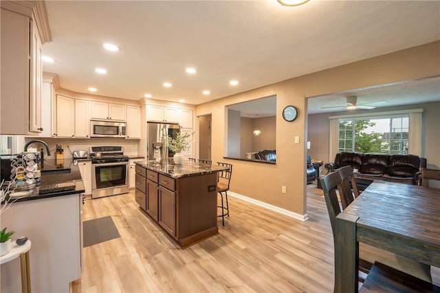 43 Dover Rd, Penn Twp, PA 15642 - kitchen featuring stainless steel appliances, light wood-type flooring, dark stone countertops, a breakfast bar, and ceiling fan