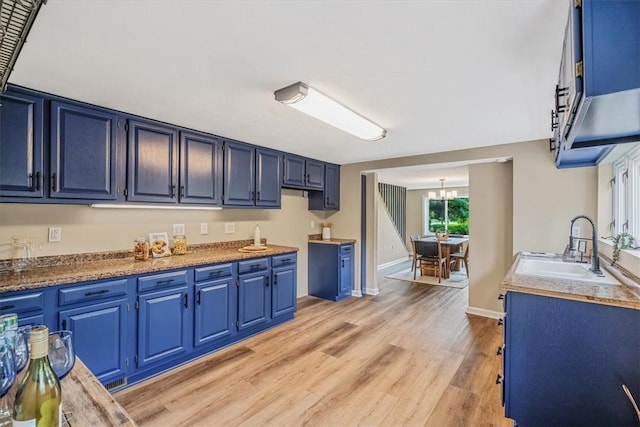 7321 Ringertown Rd, Murrysville, PA 15632 - kitchen with blue cabinets, a chandelier, and light wood-style flooring