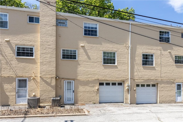 109 Raleigh Ct, Ross Twp, PA 15237 - rear view of house featuring a garage, brick siding, a chimney, and driveway