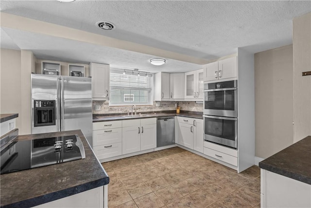 109 Raleigh Ct, Ross Twp, PA 15237 - kitchen featuring appliances with stainless steel finishes, decorative backsplash, white cabinets, and a textured ceiling