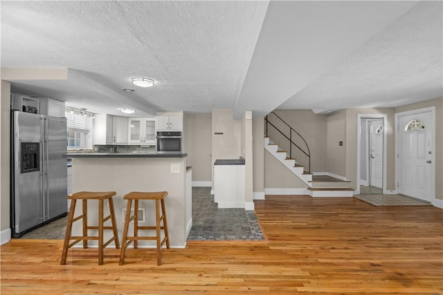 109 Raleigh Ct, Ross Twp, PA 15237 - kitchen with appliances with stainless steel finishes, a textured ceiling, light wood-style floors, white cabinets, and dark countertops