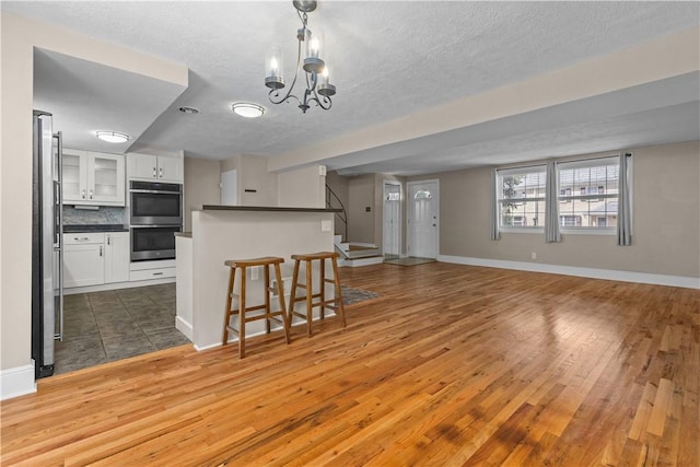 109 Raleigh Ct, Ross Twp, PA 15237 - kitchen featuring appliances with stainless steel finishes, white cabinetry, dark countertops, wood finished floors, and a kitchen bar