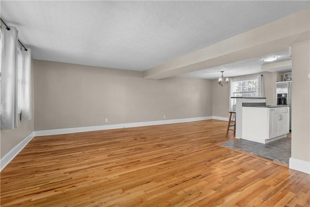 109 Raleigh Ct, Ross Twp, PA 15237 - unfurnished living room featuring light wood finished floors, a chandelier, and a textured ceiling
