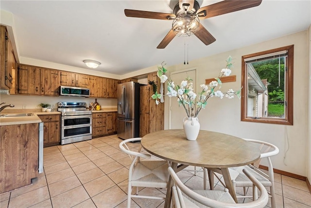 110 Four Seasons Ln, Irwin, PA 15642 - kitchen with stainless steel appliances, brown cabinets, light tile patterned flooring, ceiling fan, and light countertops