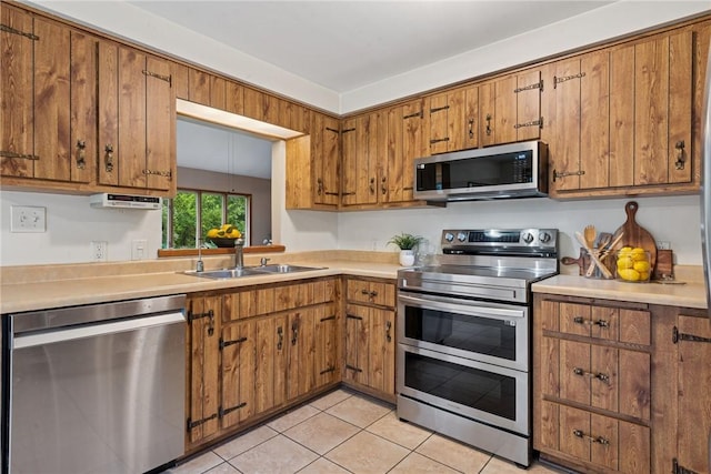 110 Four Seasons Ln, Irwin, PA 15642 - kitchen featuring appliances with stainless steel finishes, brown cabinetry, light countertops, and light tile patterned flooring