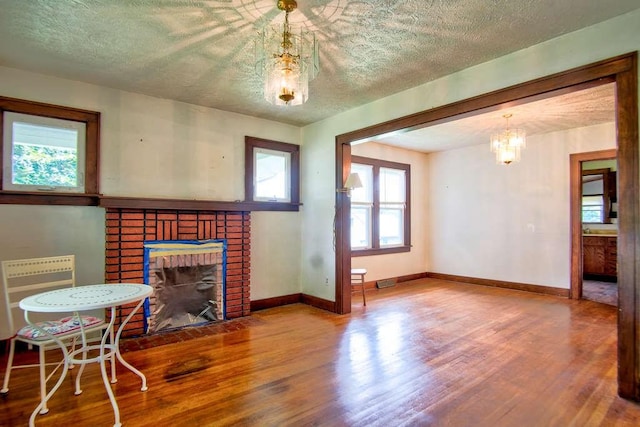 3444 Brodhead Rd, Center Twp, PA 15061 - living room with wood finished floors, a brick fireplace, a textured ceiling, and a chandelier