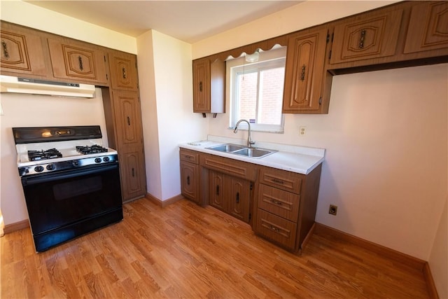 1819 Sundeman St, Troy Hill, PA 15212 - kitchen with gas stove, under cabinet range hood, brown cabinetry, light countertops, and light wood-style floors