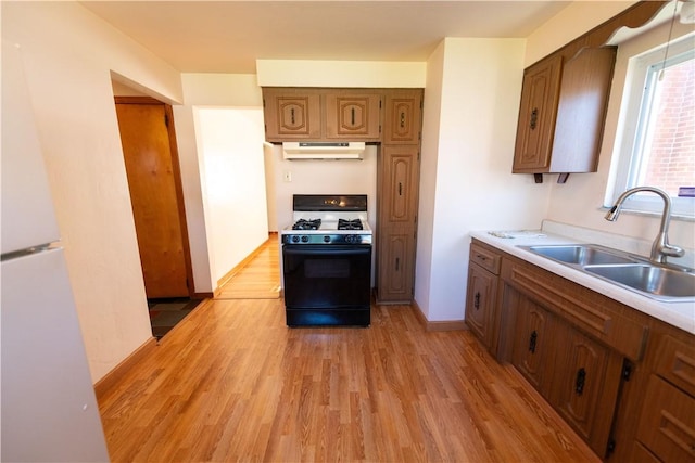 1819 Sundeman St, Troy Hill, PA 15212 - kitchen with gas range oven, under cabinet range hood, freestanding refrigerator, light wood-style floors, and brown cabinets
