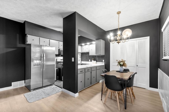 1819 Craig St, Mckeesport, PA 15132 - kitchen featuring stainless steel fridge, light wood-style floors, a chandelier, light countertops, and a textured ceiling