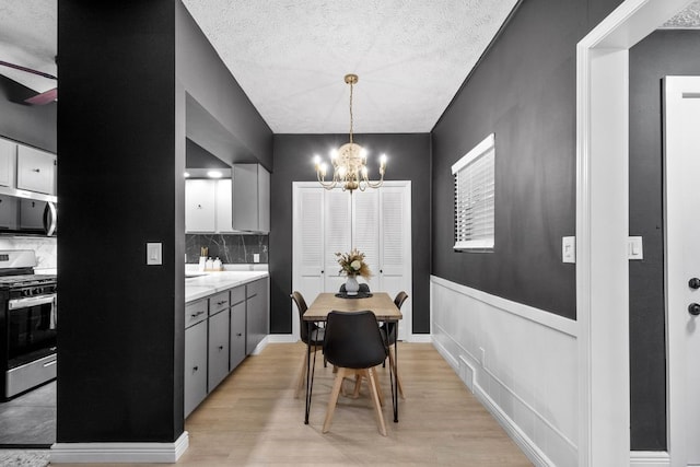1819 Craig St, Mckeesport, PA 15132 - dining room with a chandelier, light wood-style floors, and a textured ceiling