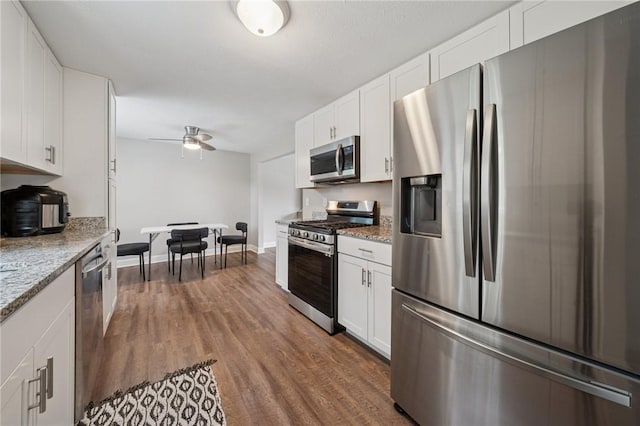 2047 Haymaker Rd, Monroeville, PA 15146 - kitchen featuring appliances with stainless steel finishes, dark wood-style flooring, white cabinets, ceiling fan, and light stone counters