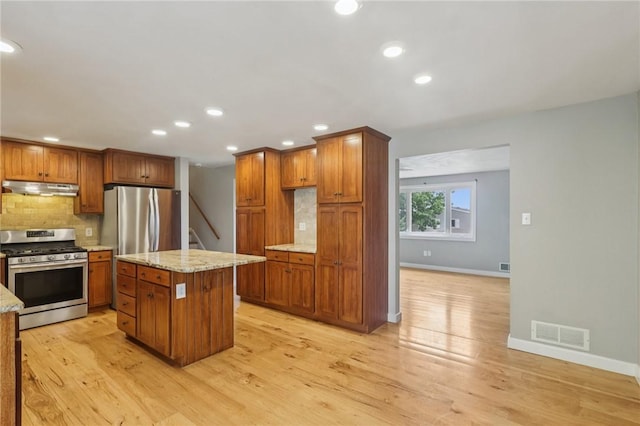 1717 Gina Dr, West Mifflin, PA 15122 - kitchen with appliances with stainless steel finishes, under cabinet range hood, backsplash, brown cabinets, and light stone counters