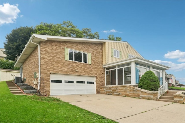 1717 Gina Dr, West Mifflin, PA 15122 - view of front facade with an attached garage, driveway, a sunroom, brick siding, and a front lawn
