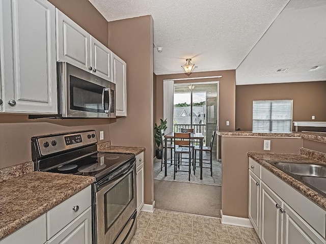 310 Stockton Rdg, Cranberry Twp, PA 16066 - kitchen featuring stainless steel appliances, a textured ceiling, white cabinets, light colored carpet, and dark countertops