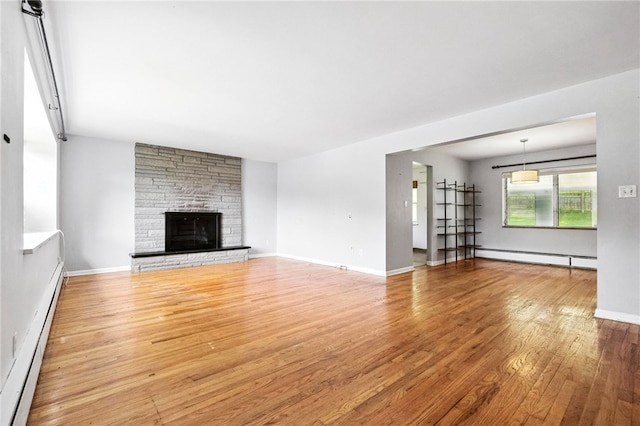110 Marian Ave, Shaler, PA 15116 - unfurnished living room featuring a baseboard heating unit, wood finished floors, and a stone fireplace