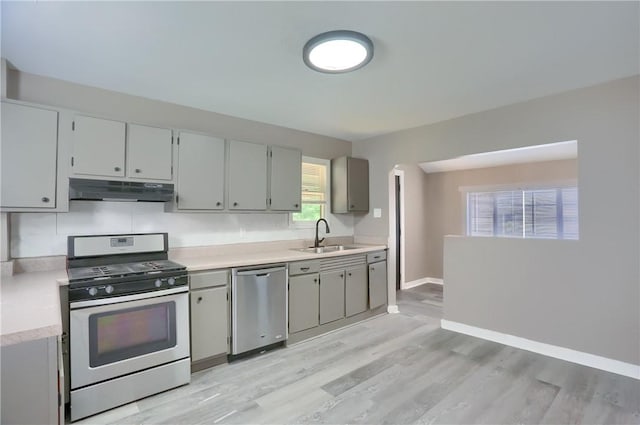 505 Bellwood Rd, West Mifflin, PA 15122 - kitchen featuring stainless steel appliances, under cabinet range hood, light countertops, light wood finished floors, and gray cabinetry