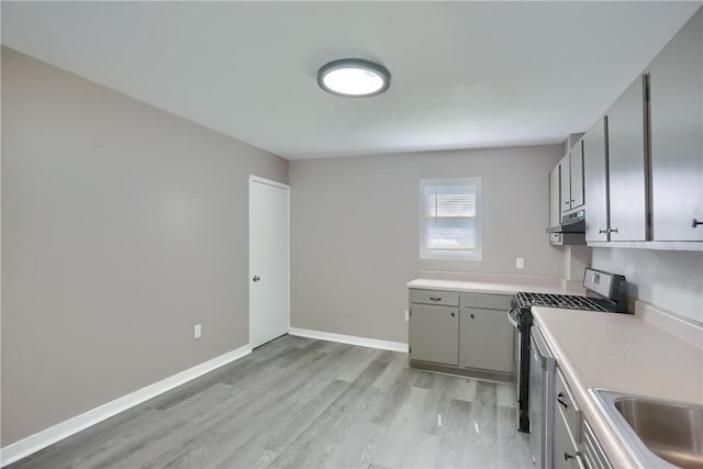 505 Bellwood Rd, West Mifflin, PA 15122 - kitchen with stainless steel gas stove, exhaust hood, light wood-type flooring, light countertops, and gray cabinets