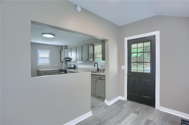505 Bellwood Rd, West Mifflin, PA 15122 - kitchen featuring stainless steel range oven, gray cabinets, under cabinet range hood, light wood-style floors, and vaulted ceiling