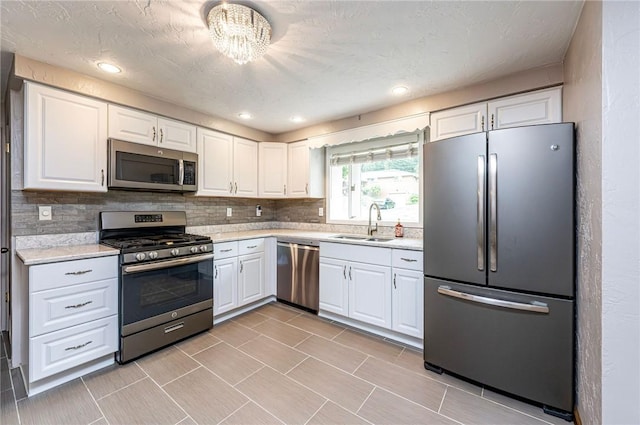 12220 Herold Dr, North Huntingdon, PA 15642 - kitchen with stainless steel appliances, light countertops, white cabinetry, decorative backsplash, and a chandelier