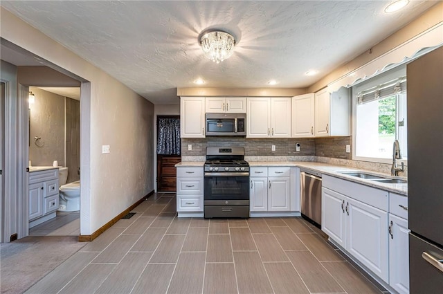12220 Herold Dr, North Huntingdon, PA 15642 - kitchen featuring appliances with stainless steel finishes, white cabinets, a chandelier, and tasteful backsplash