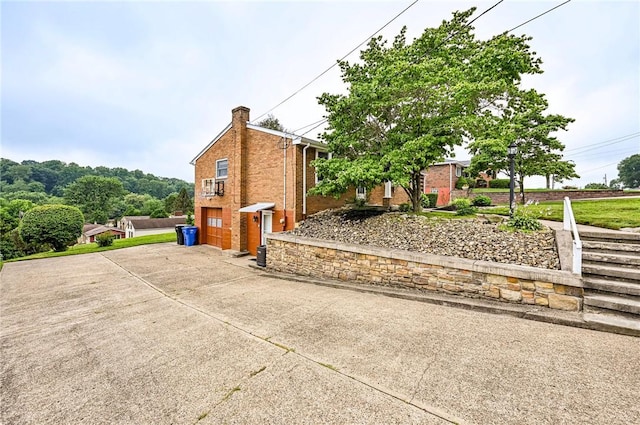 12220 Herold Dr, North Huntingdon, PA 15642 - view of side of home featuring driveway, brick siding, a chimney, and an attached garage