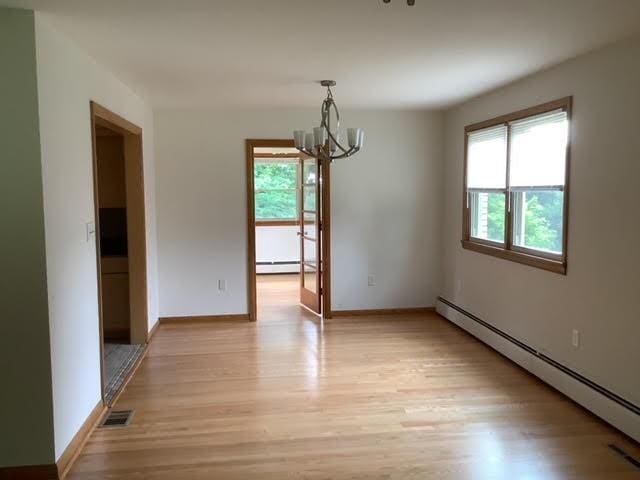 120 Rothen Ave, Twp Of But Nw, PA 16001 - unfurnished dining area with a baseboard heating unit, a chandelier, light wood-style floors, and a baseboard radiator