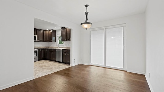 4952 Flamingo Dr, Whitehall, PA 15236 - kitchen with appliances with stainless steel finishes, dark brown cabinetry, light wood-style floors, light countertops, and pendant lighting