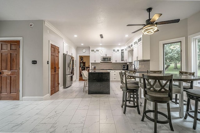 117 Cidar Ln, Peters Twp, PA 15317 - kitchen with appliances with stainless steel finishes, light marble finish flooring, a ceiling fan, a breakfast bar area, and decorative backsplash